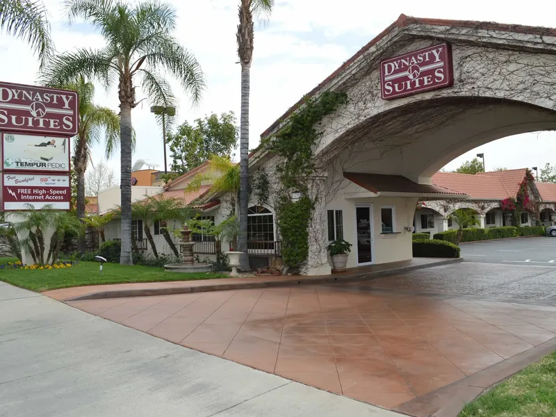 Dynasty Suites Redlands front exterior with palm trees and porte cochere.